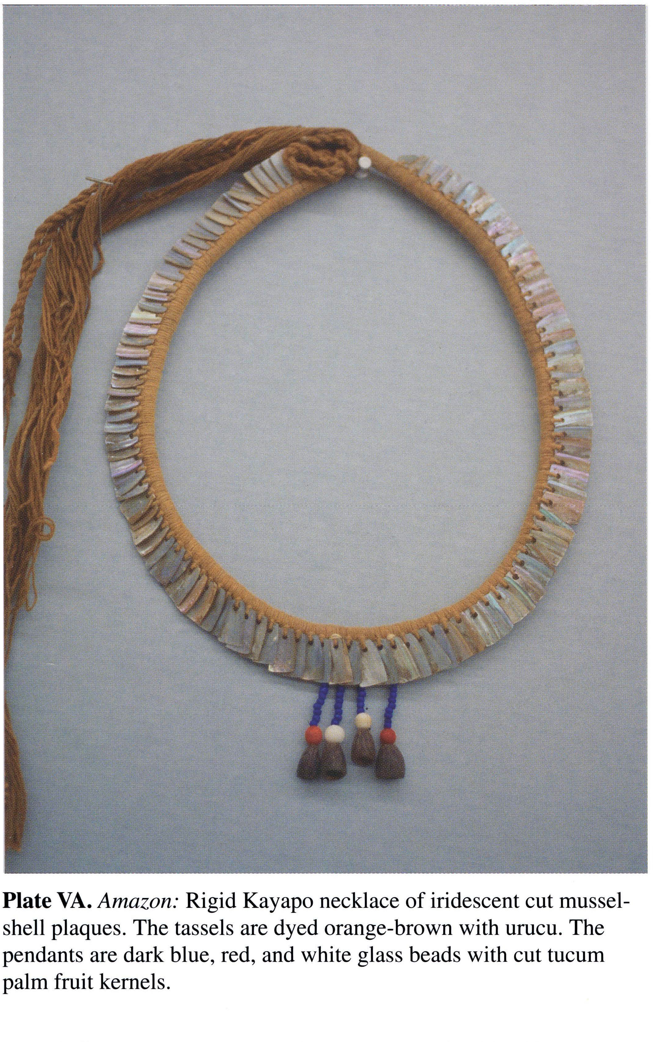 Plate VA Amazon: Rigid Kayapo necklace of iridescent cut musselshell plaques. The tassels are dyed orange-brown with urucu. The pendants are dark blue, red, and white glass beads with cut tucum palm fruit kernels.
